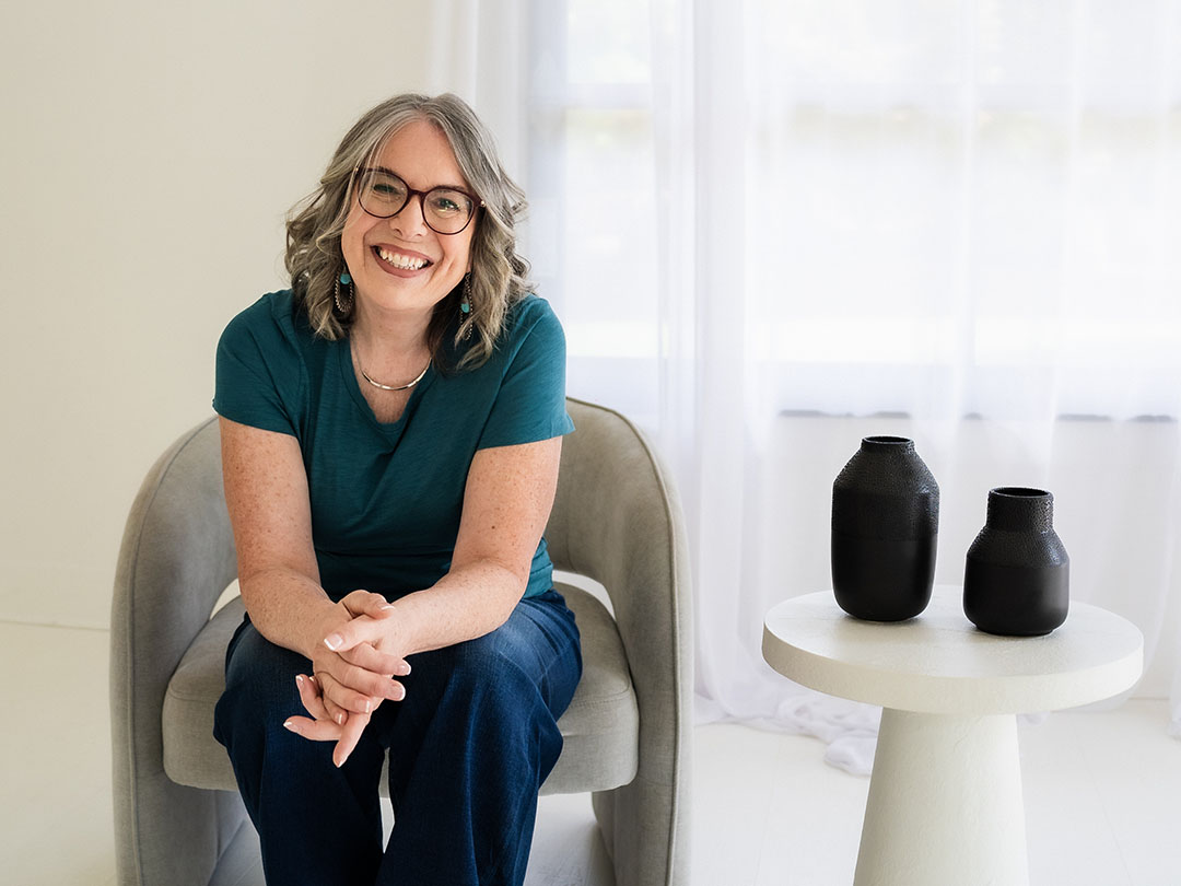 Lynda Grodd sitting in a sofa chair, smiling